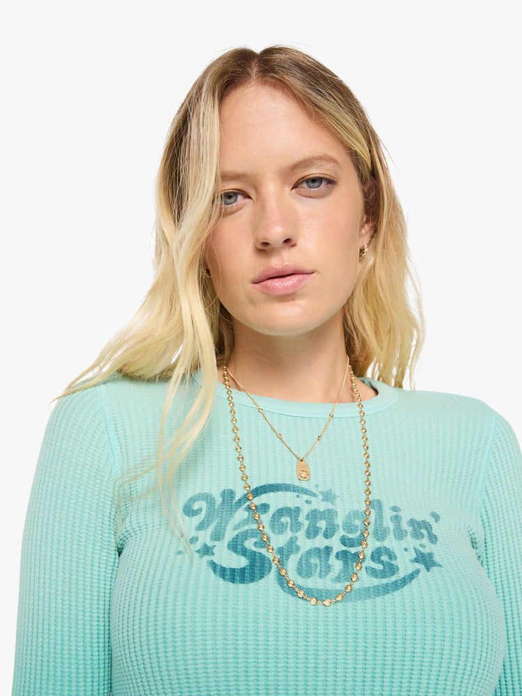 Close up view of a woman in long sleeve shirt sun-faded turquoise with a vintage-inspired Western graphic across the chest.