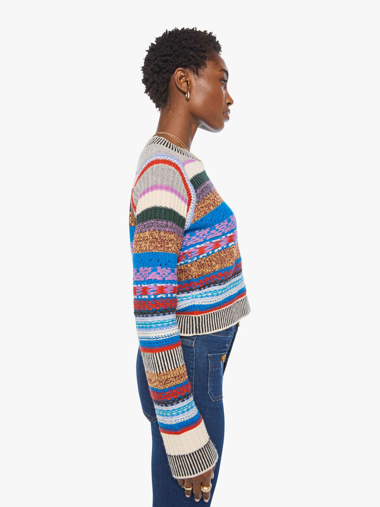 Side view of a woman in a multicolored stripes with knit details crewneck sweater with extra-long sleeves and a cropped fit.