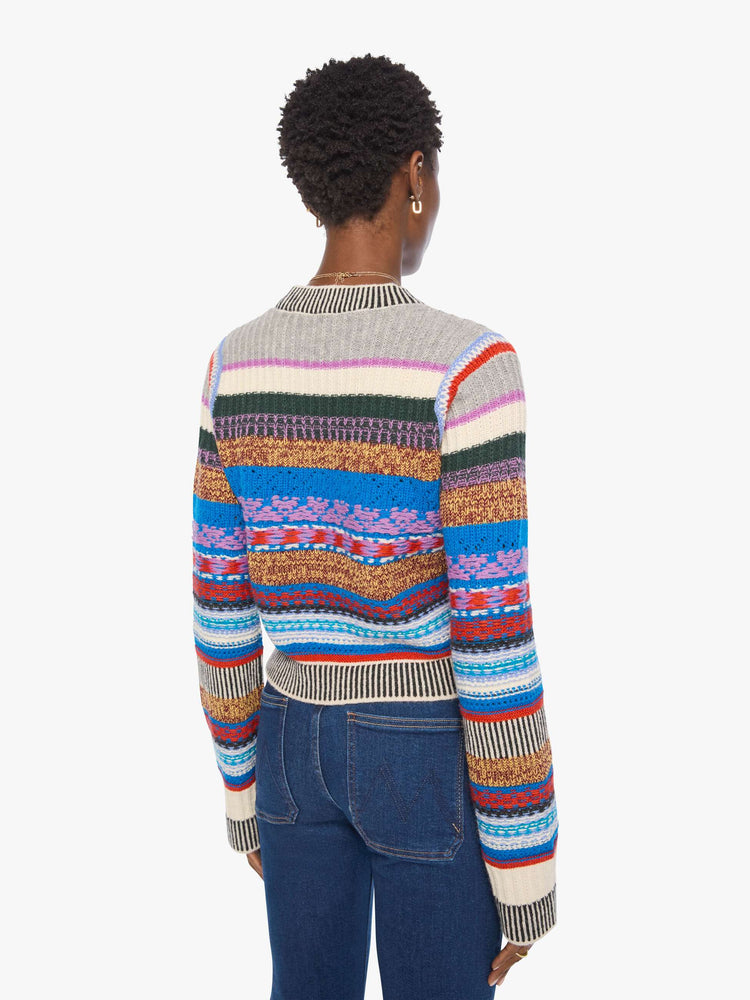 Back view of a woman in a multicolored stripes with knit details crewneck sweater with extra-long sleeves and a cropped fit.
