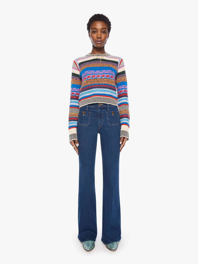 Full body view of a woman in a multicolored stripes with knit details crewneck sweater with extra-long sleeves and a cropped fit.