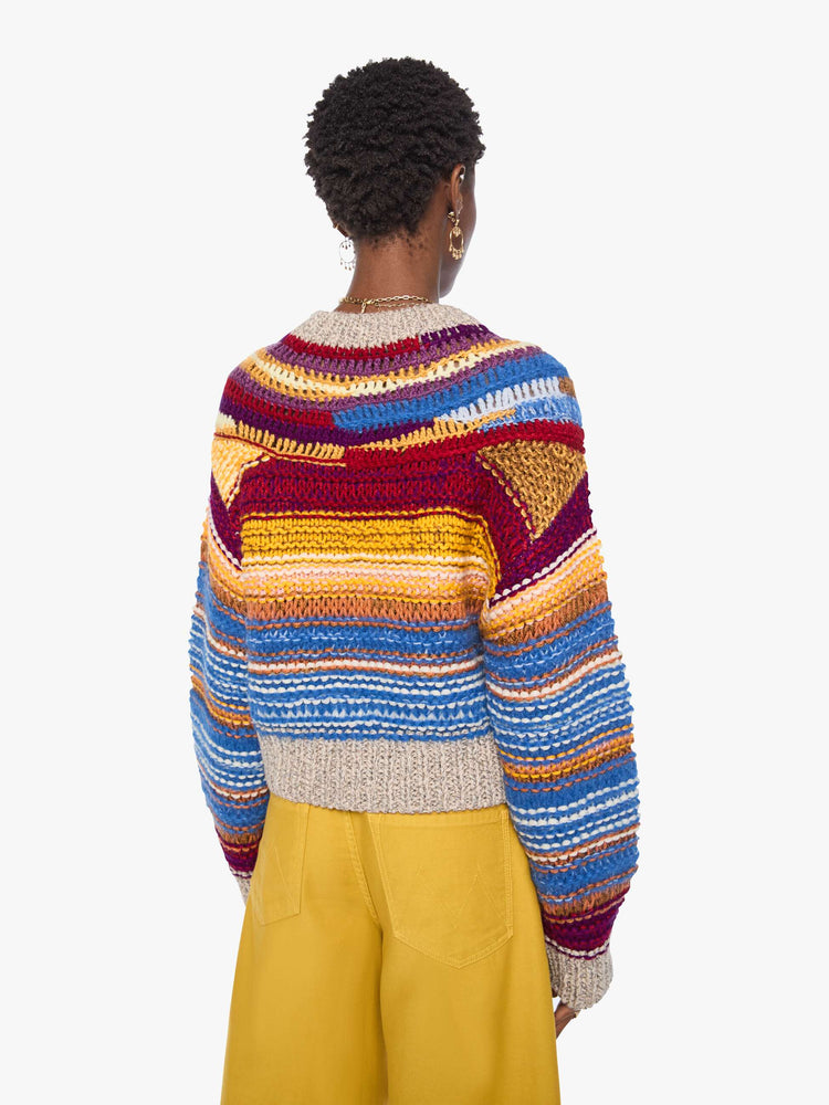 Back view of a woman in a crewneck sweater is designed with colorful horizontal stripes, textured details and ribbed grey hems.