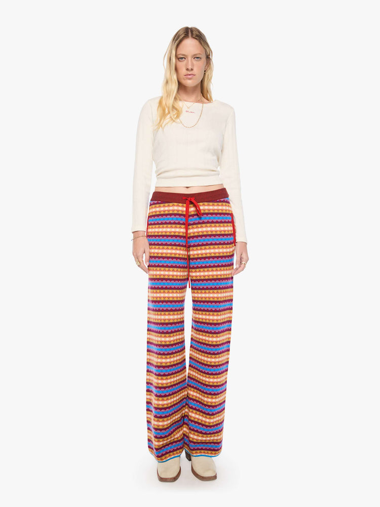 Front view of a woman in a golden yellow, maroon, white and blue jacquard-print stripes wide-leg pants with an elastic drawstring waistband and a loose, comfortable fit.