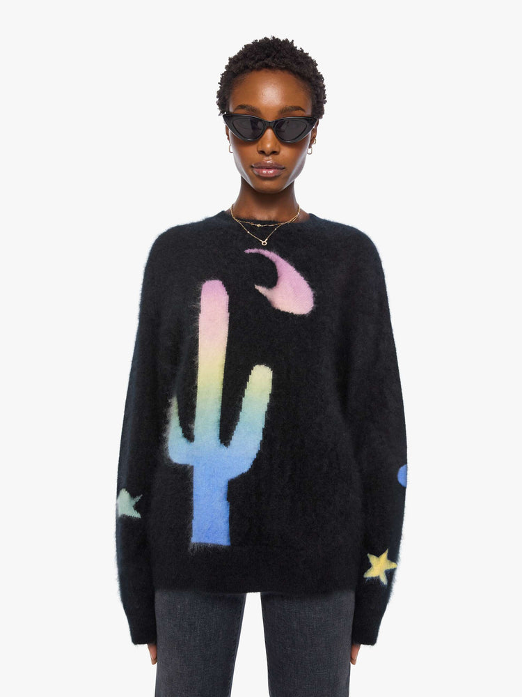 Front view of a woman in sweater is designed in black with a rainbow cactus and moon across the chest.
