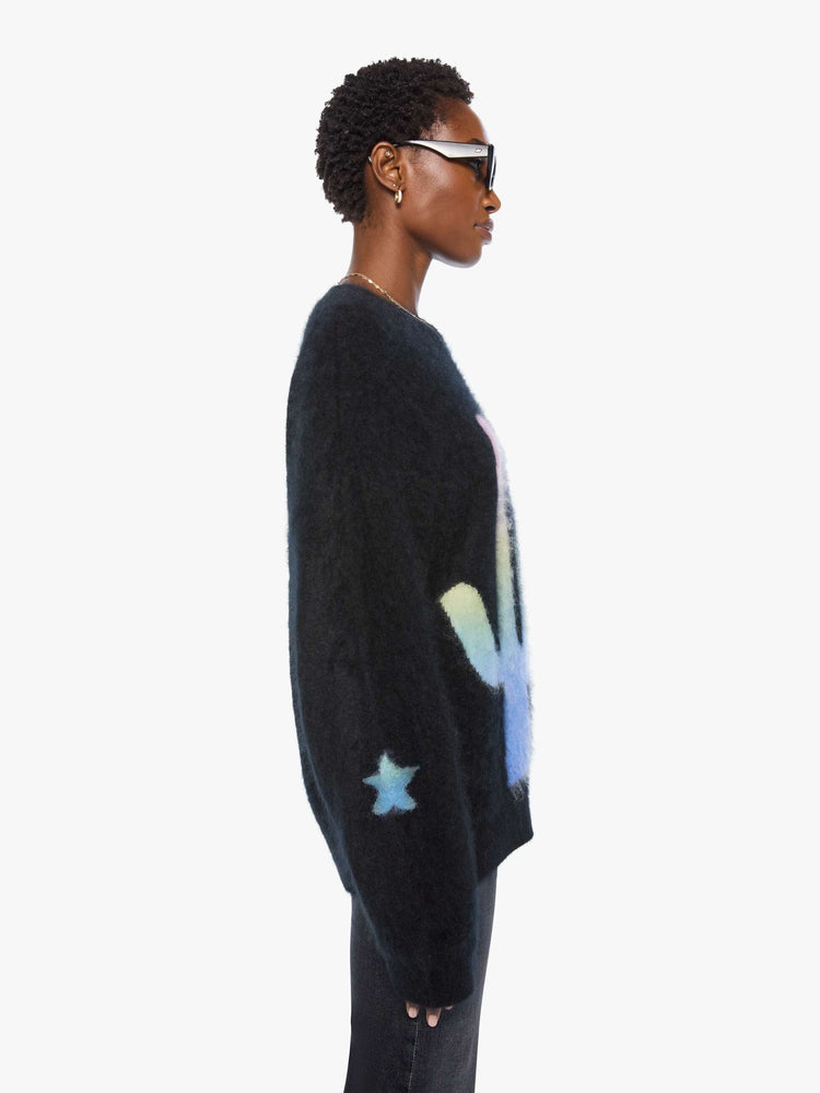 Side view of a woman in sweater is designed in black with a rainbow cactus and moon across the chest.
