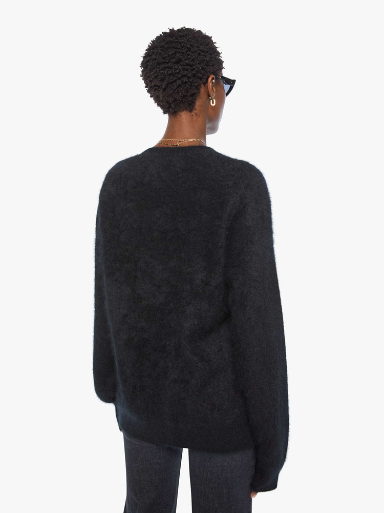 Back view of a woman in sweater is designed in black with a rainbow cactus and moon across the chest.
