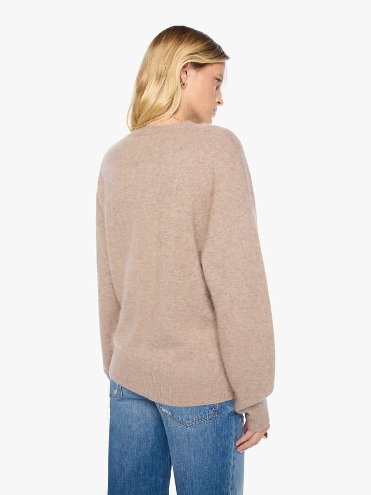 Back view of a woman in a sweater designed in a warm tan with a knit Pegasus graphic in light blue on the front and MOTHER's name on the hip.