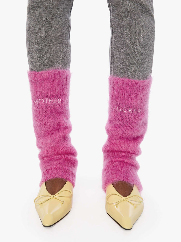 Front view of a woman in a legwarmer designed in a hot pink mohair blend with ribbed hems and MOTHER FUCKER in white across the front.