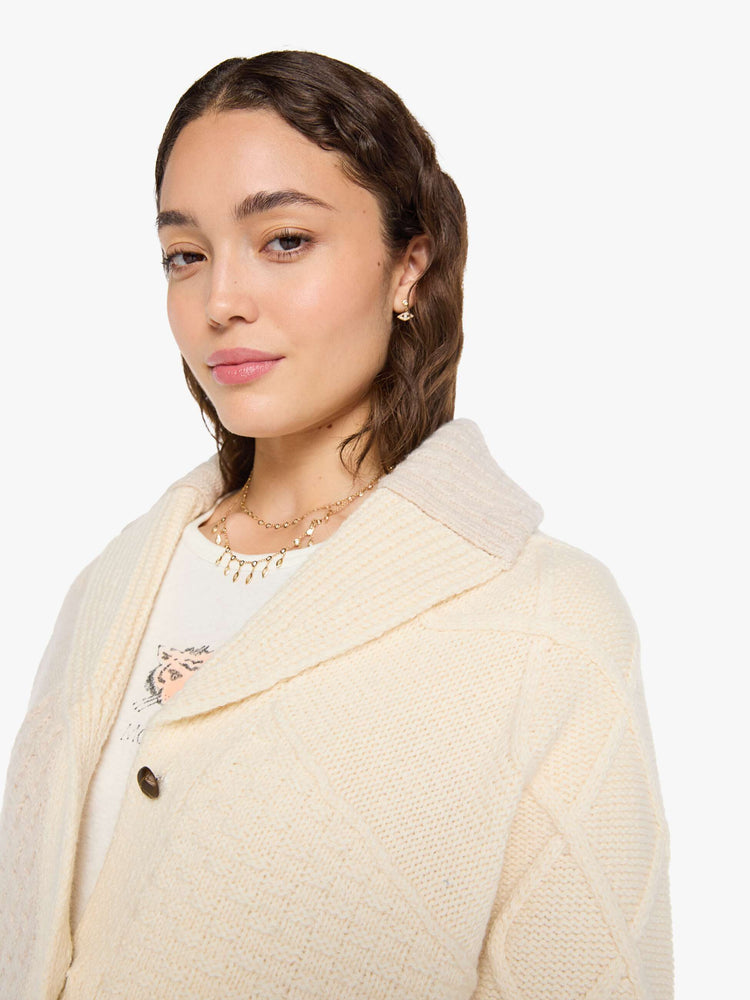 Close up view of a woman in a chunky cardigan with a shawl collar, V-neck, 3-button closure, ribbed hems and a slightly cropped fit. 