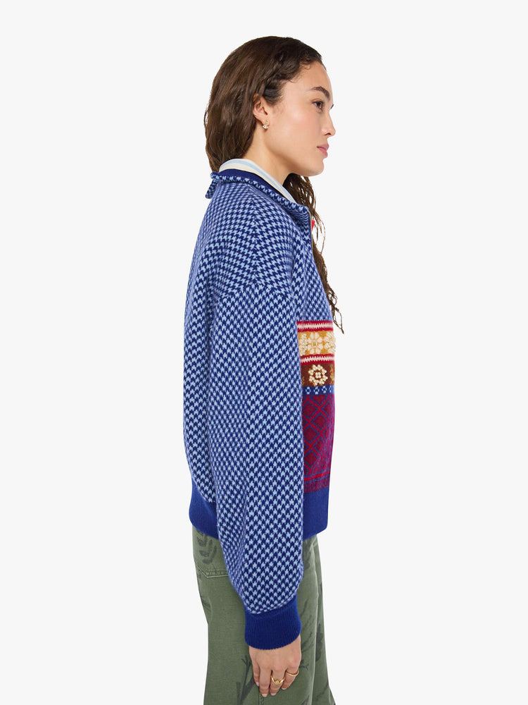 Side view of a woman in a navy and light blue Fleur de Lys pattern with colorful knit sections in red, golden yellow and maroon across the body and pearl beaded details sweater.
