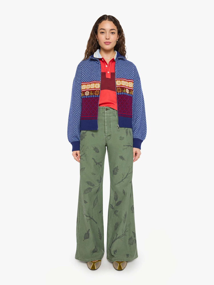 Full body view of a woman in a navy and light blue Fleur de Lys pattern with colorful knit sections in red, golden yellow and maroon across the body and pearl beaded details sweater.