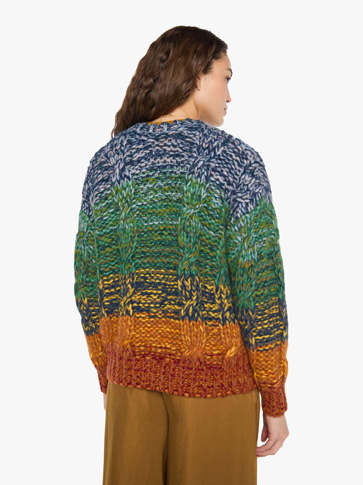 Back view of a woman in a rainbow stripe oversized cardigan with a crewneck, drop shoulders, ribbed hems and buttons down the front.