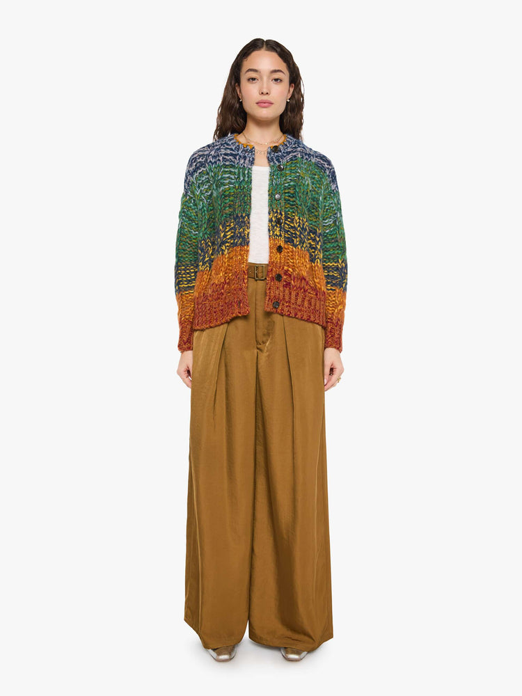 Front view of a woman in a rainbow stripe oversized cardigan with a crewneck, drop shoulders, ribbed hems and buttons down the front.