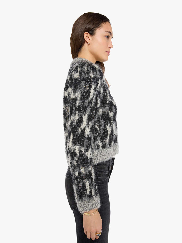 Side view of a woman in a sweater in a black, grey and white with beaded details throughout and faux-suede buttons down the front.