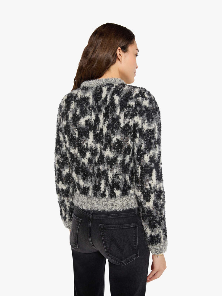 Back view of a woman in a sweater in a black, grey and white with beaded details throughout and faux-suede buttons down the front.