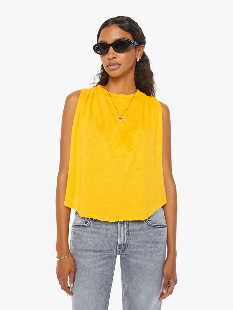 Front view of a woman in a yellow crewneck tank with gathered shoulders, a curved hem and a loose, oversized fit. Paired with grey jeans. 