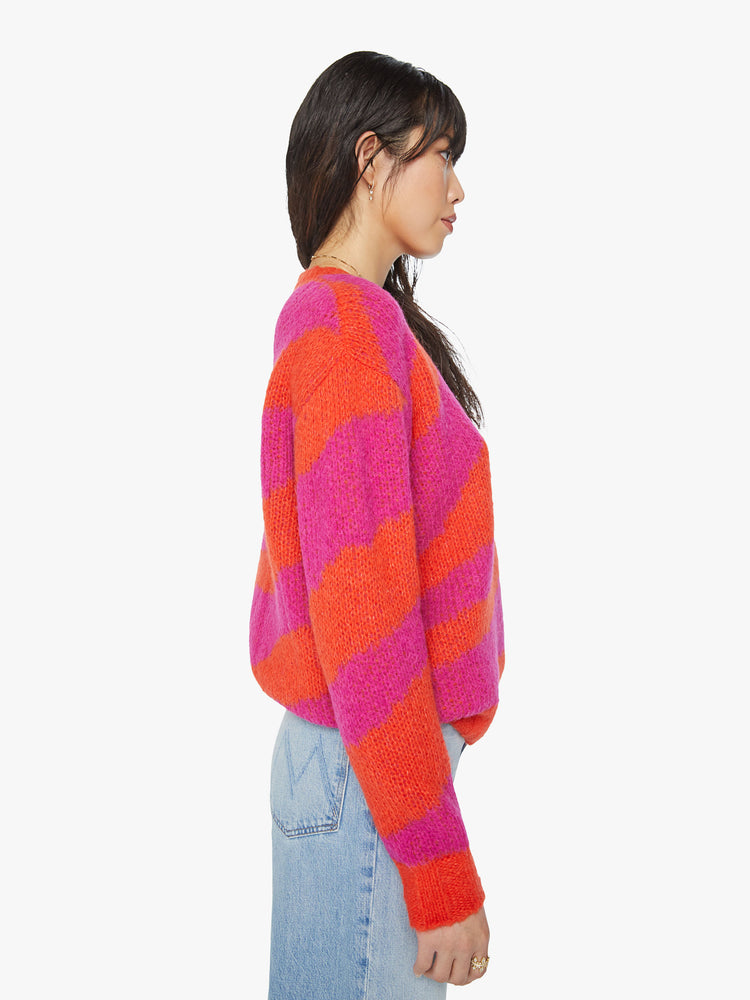 Side view of a woman oversized crewneck sweater with drop shoulders, long roomy sleeves and a hip-length hem in bright red and hot pink oversized zebra print.