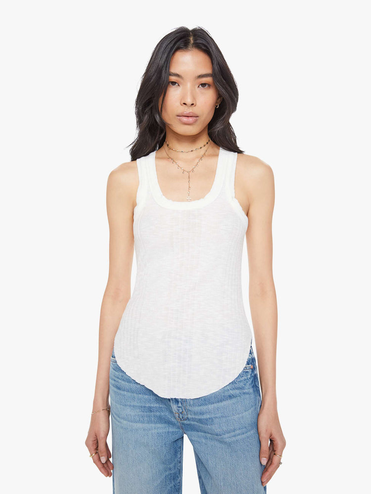 Front view of a woman in a white scoop neck tank with wide straps, a narrow fit and a curved hem. 