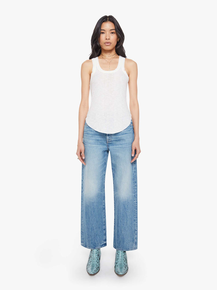 full body view of a woman in a white scoop neck tank with wide straps, a narrow fit and a curved hem. 