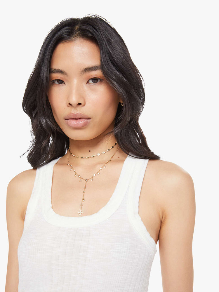 Close upview of a woman in a white scoop neck tank with wide straps, a narrow fit and a curved hem. 