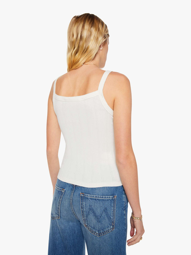 Back view of a woman in a square-neck tank with thick straps and a narrow fit. Made from 100% cotton, the top is designed in white with pointelle details and MOTHER's name embroidered in red on the front.