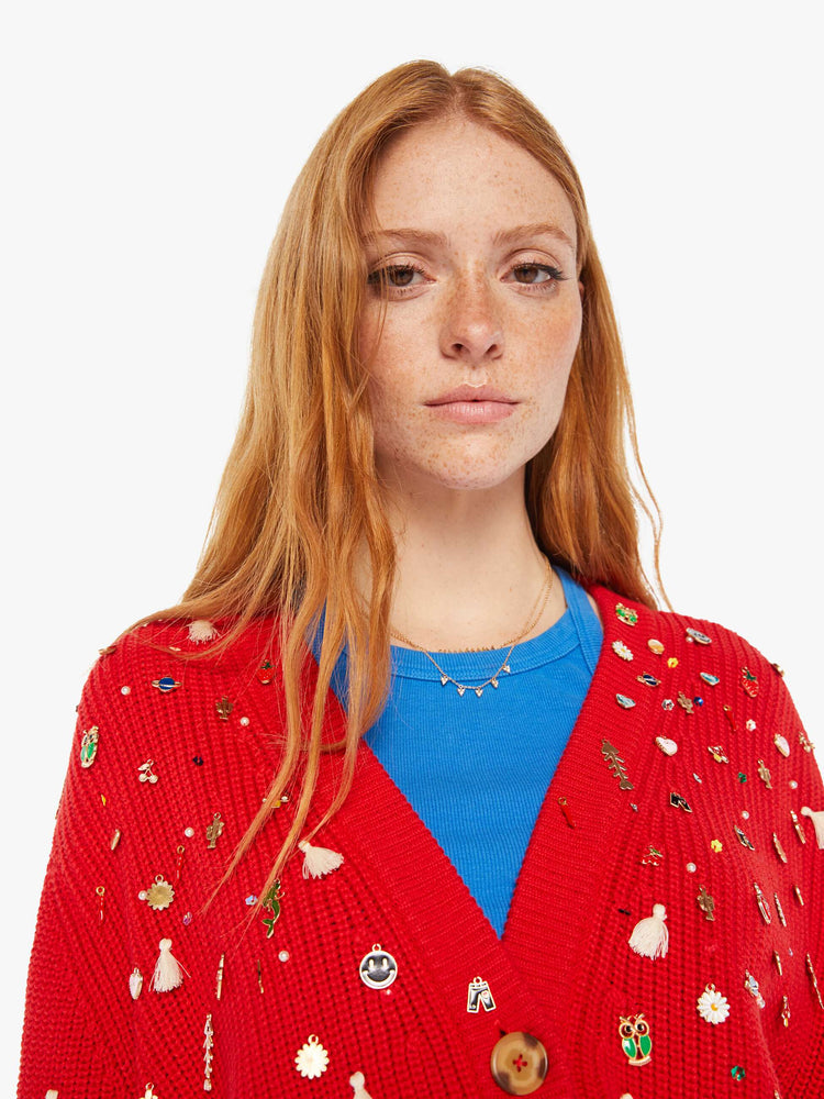 Close up view of a woman red with colorful charms, beads and tassels V-neck cardigan with long balloon sleeves, drop shoulders and ribbed hems.