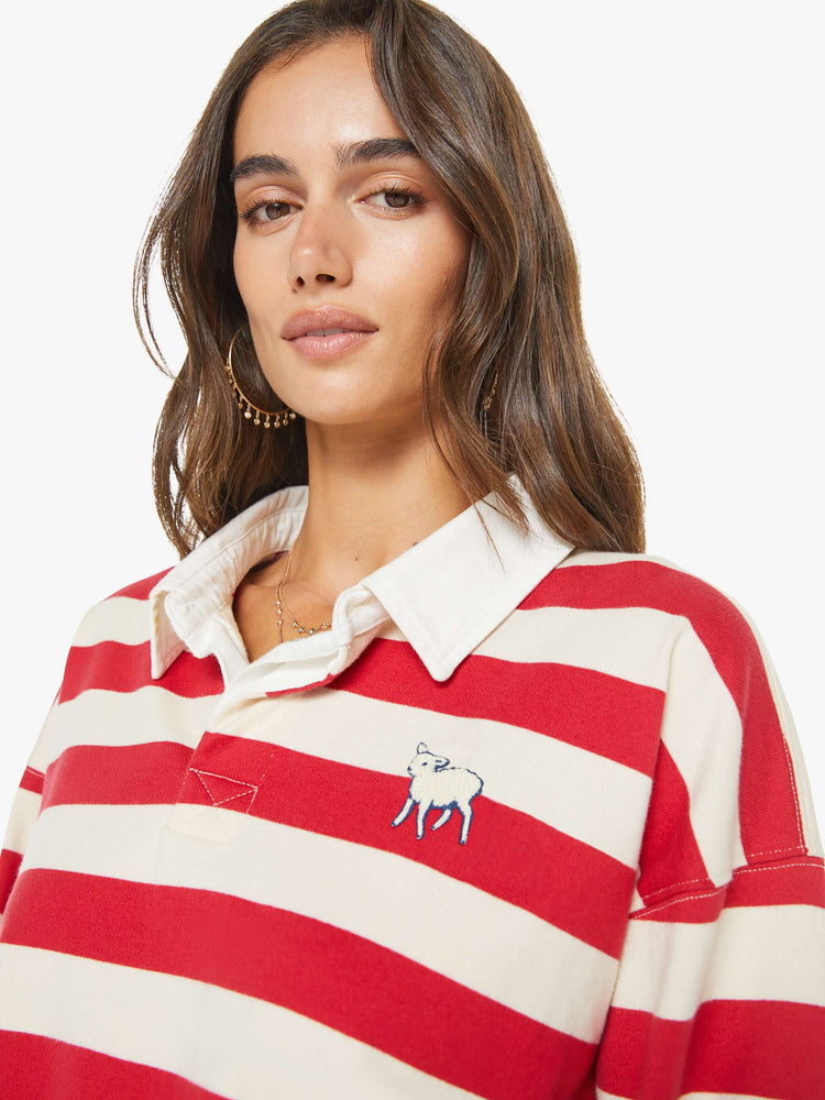 Close up view of a woman in a  top designed in off-white and red stripes with a fuzzy lamb patch on the chest.