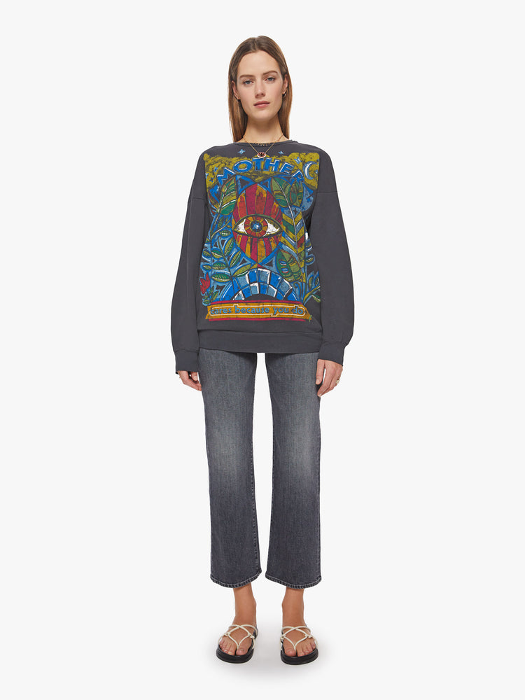 Full body view of a woman crewneck sweatshirt with dropped sleeves, a relaxed fit and an extra-long hemline in a washed black hue with a faded psychedelic graphic.