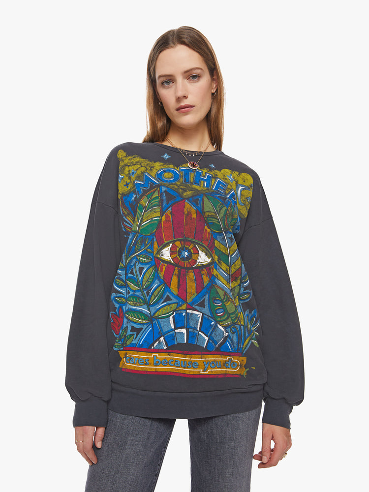 Front view of a woman crewneck sweatshirt with dropped sleeves, a relaxed fit and an extra-long hemline in a washed black hue with a faded psychedelic graphic.