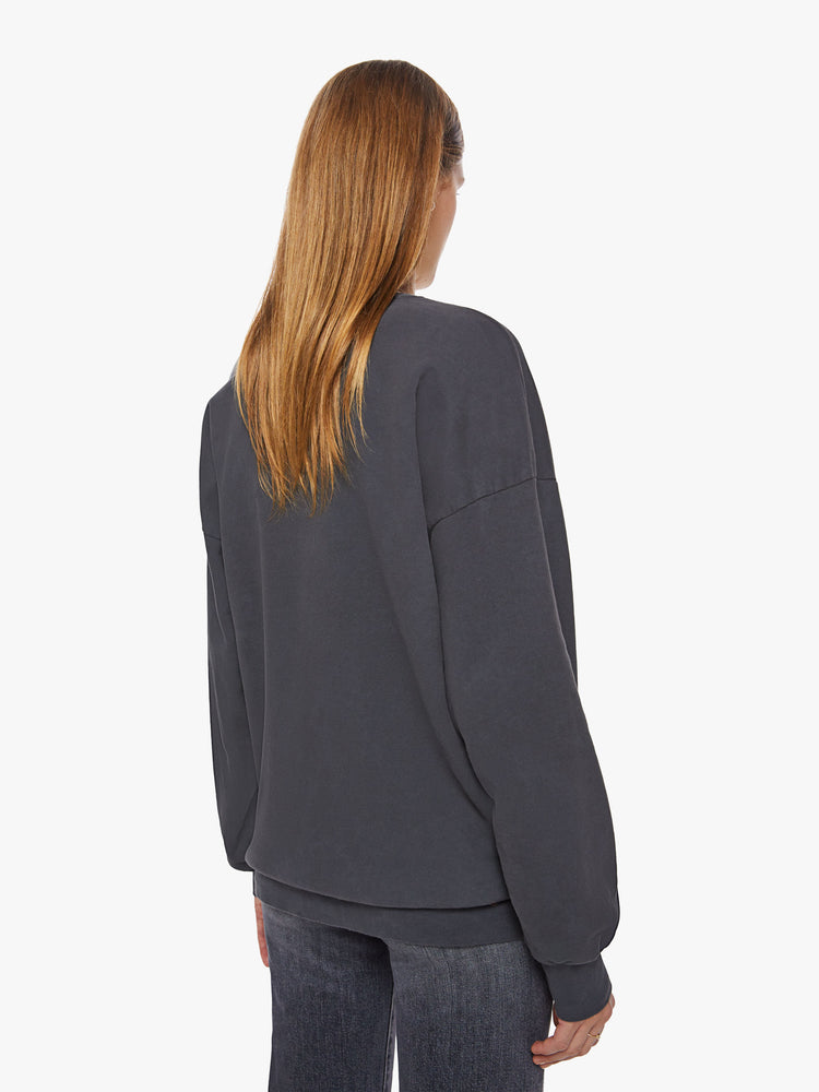 Back view of a woman crewneck sweatshirt with dropped sleeves, a relaxed fit and an extra-long hemline in a washed black hue with a faded psychedelic graphic.