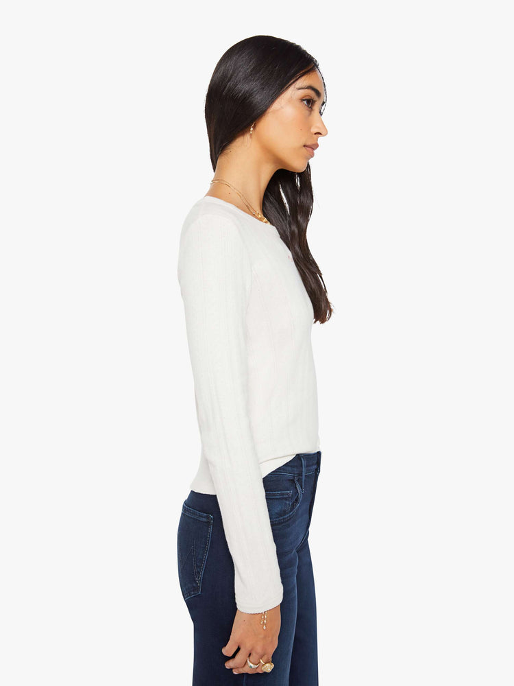 Side view of a woman in a white wth MOTHER in red detail crewneck top with long sleeves and a narrow fit. 