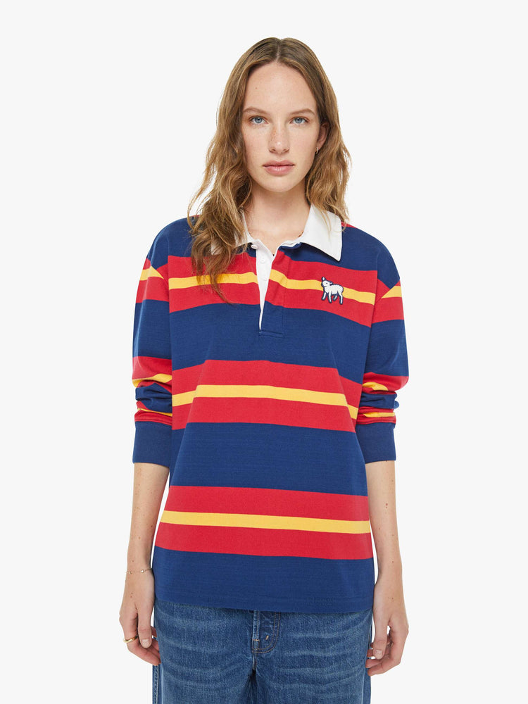 Front view of a woman in a shirt designed in red, navy and golden-yellow stripes with a fuzzy lamb patch on the chest.
