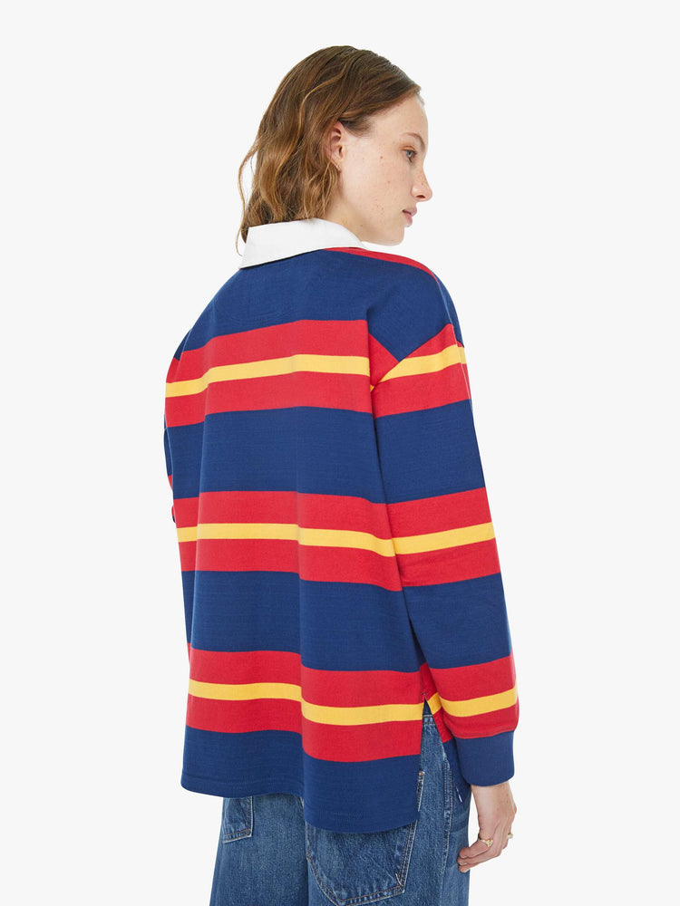 Back view of a woman in a shirt designed in red, navy and golden-yellow stripes with a fuzzy lamb patch on the chest.