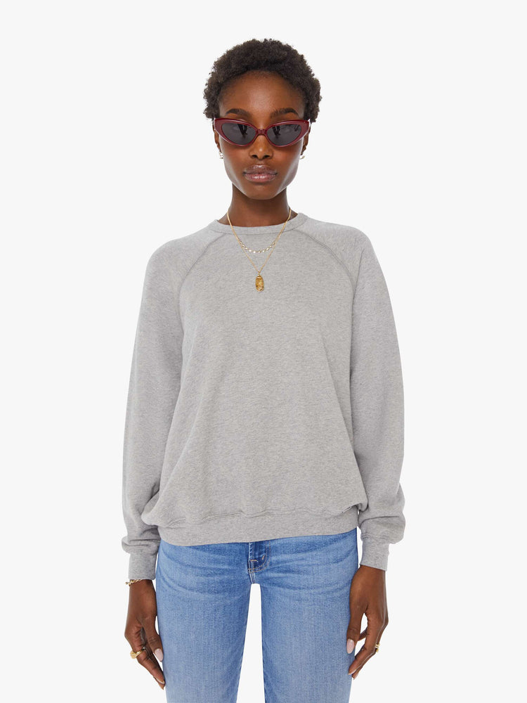 Front view of a woman in a grey oversized raglan sweatshirt with a crewneck, ribbed hems and a slightly cropped fit.