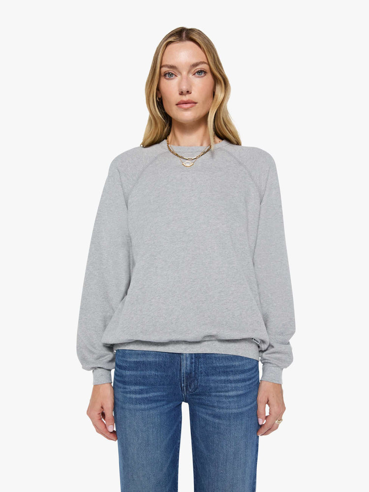 Front view of a woman in a grey oversized raglan sweatshirt with a crewneck, ribbed hems and a slightly cropped fit.