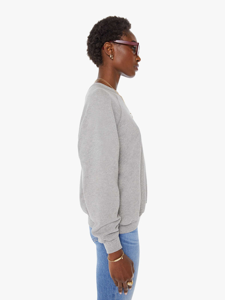 Side view of a woman in a grey oversized raglan sweatshirt with a crewneck, ribbed hems and a slightly cropped fit.