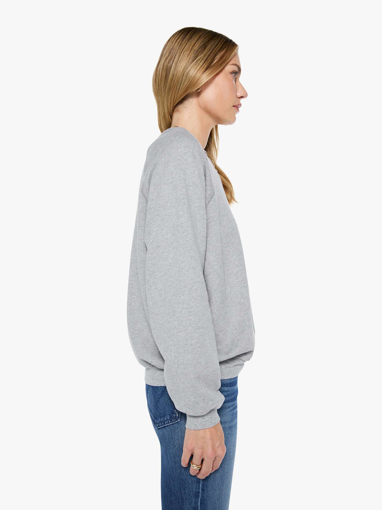 Side view of a woman in a grey oversized raglan sweatshirt with a crewneck, ribbed hems and a slightly cropped fit.