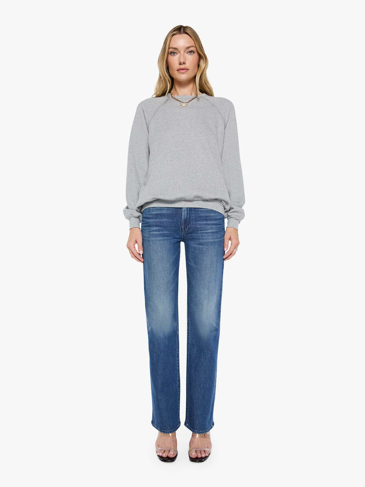 Front full body view of a woman in a grey oversized raglan sweatshirt with a crewneck, ribbed hems and a slightly cropped fit.