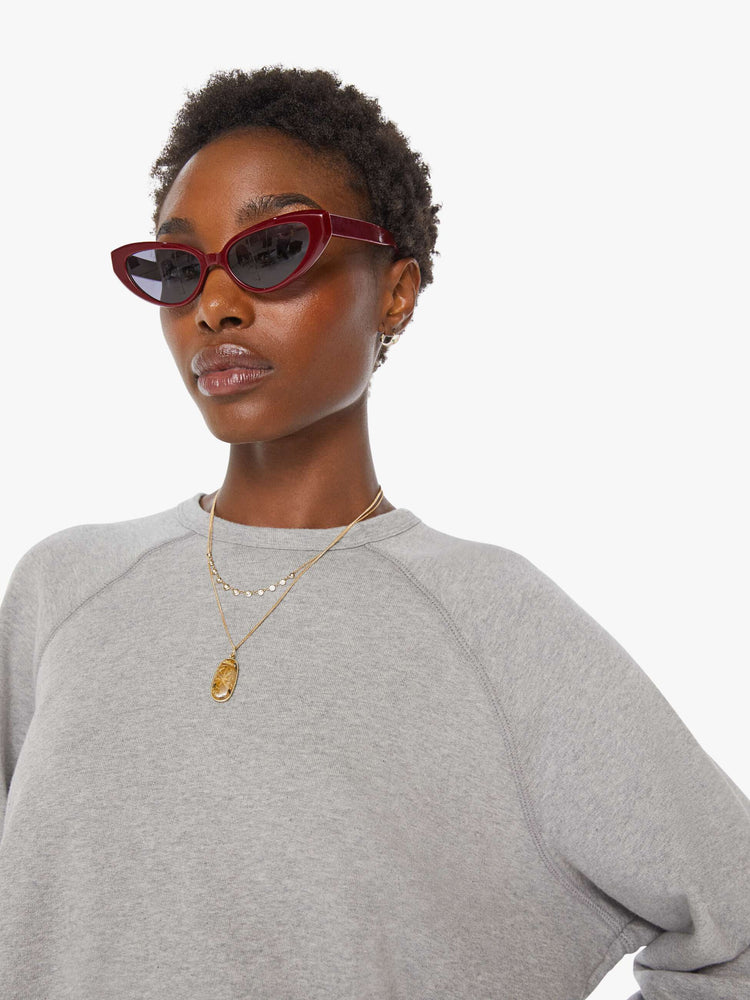 Close up view of a woman in a grey oversized raglan sweatshirt with a crewneck, ribbed hems and a slightly cropped fit.