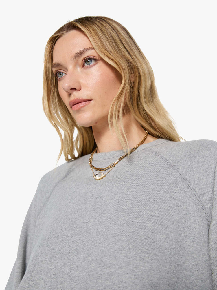 Close up view of a woman in a grey oversized raglan sweatshirt with a crewneck, ribbed hems and a slightly cropped fit.