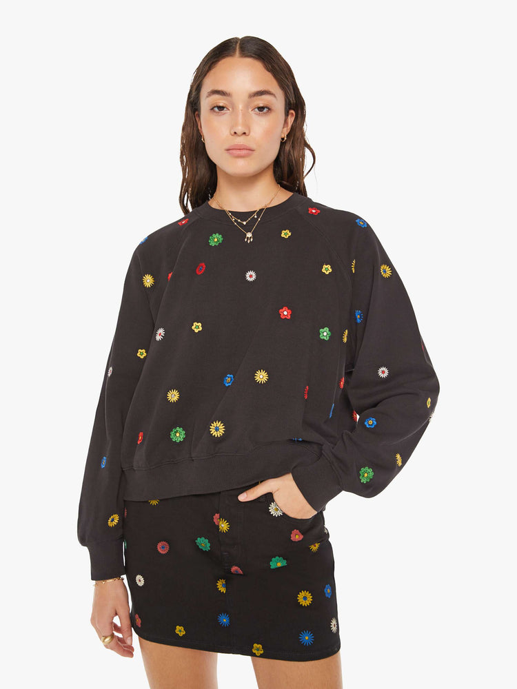 Front view of a woman oversized sweatshirt in black with embroidered with colorful flowers throughout. 