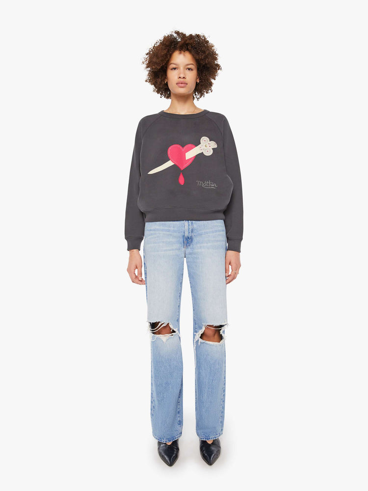 Full body view of a woman in a faded black with graphic in front oversized raglan sweatshirt with a crewneck, ribbed hems and a slightly cropped fit. 