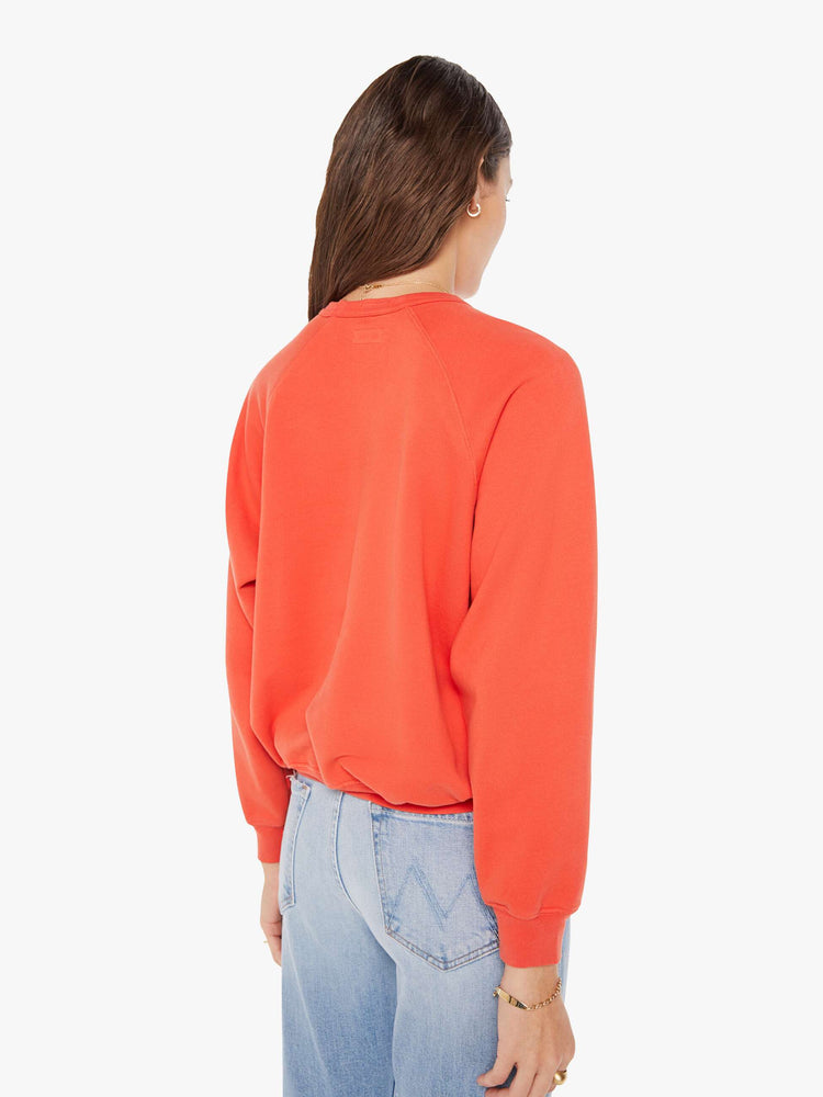 Back view of a woman in a oversized raglan sweatshirt with ribbed hems and slightly cropped fit in red with blue text graphic.