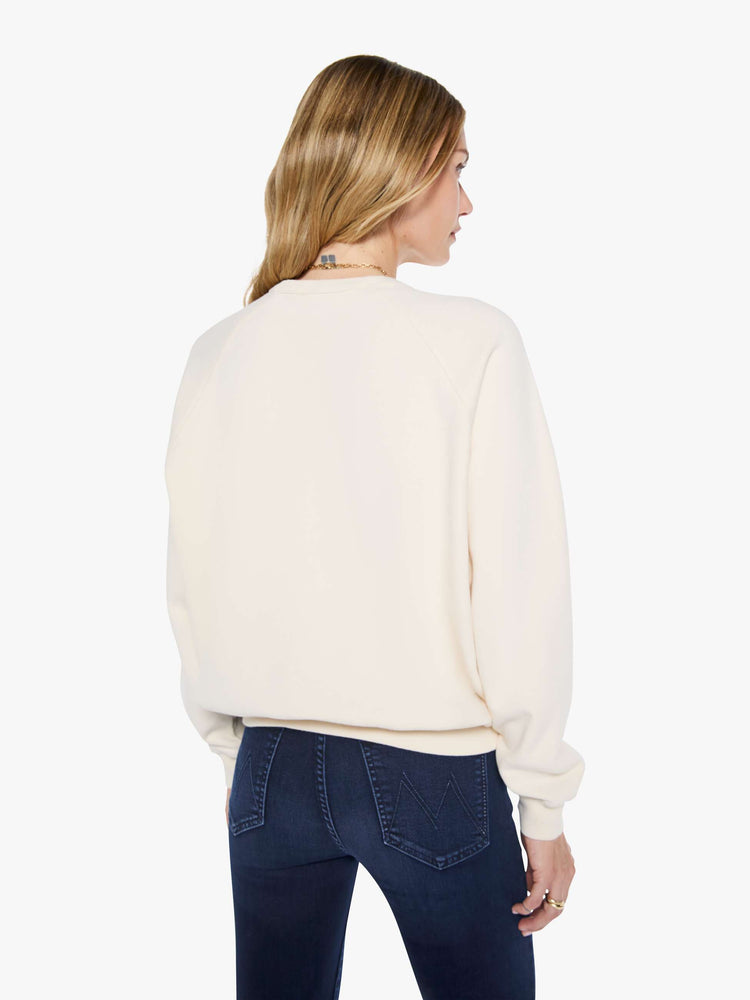 Back view of a woman in a cream oversized raglan sweatshirt with a crewneck, ribbed hems and a slightly cropped fit.