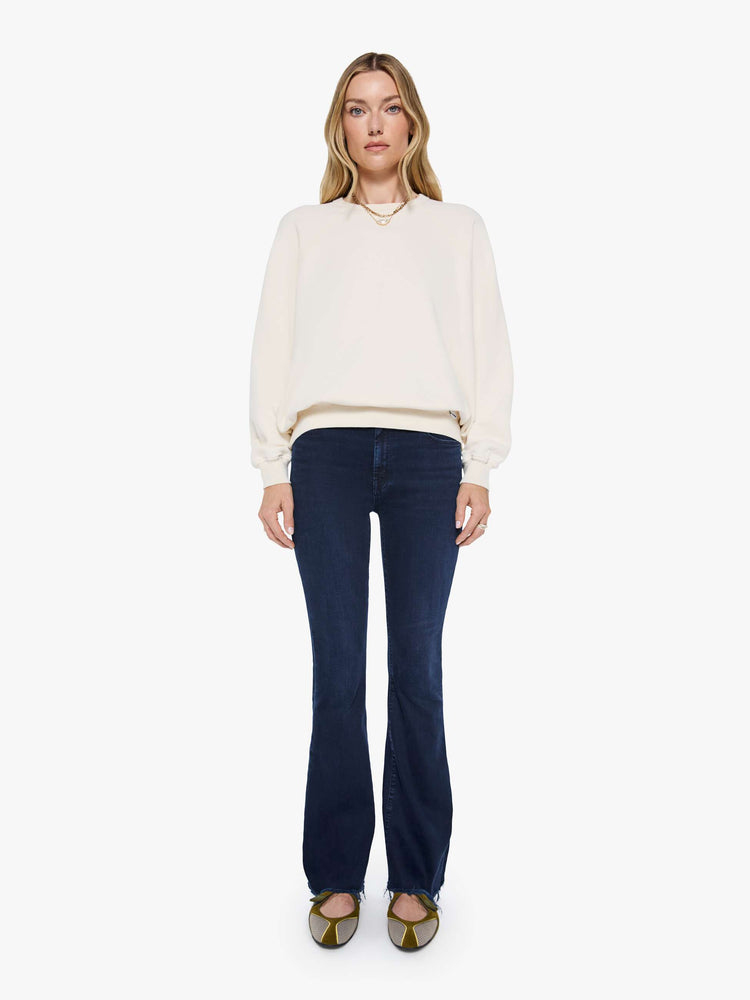 Full body view of a woman in a cream oversized raglan sweatshirt with a crewneck, ribbed hems and a slightly cropped fit.