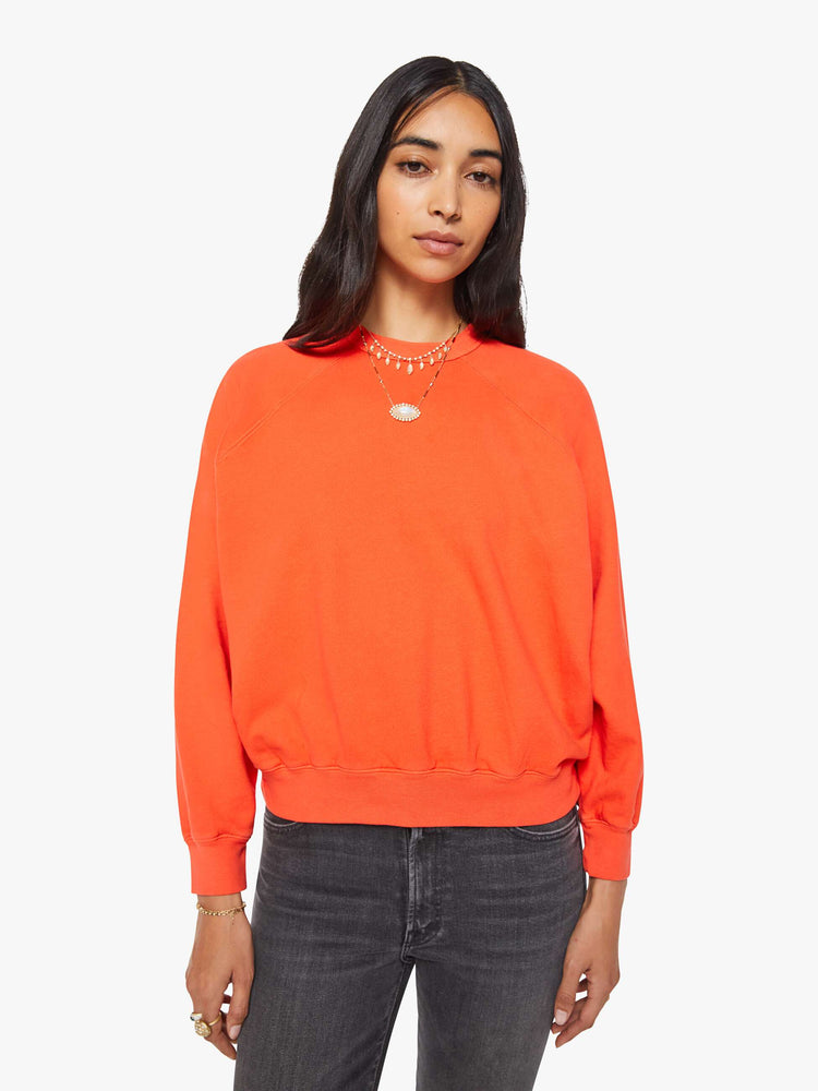 Front view of a woman in a bright orange  sweatshirt with a crewneck, ribbed hems and a slightly cropped fit. 