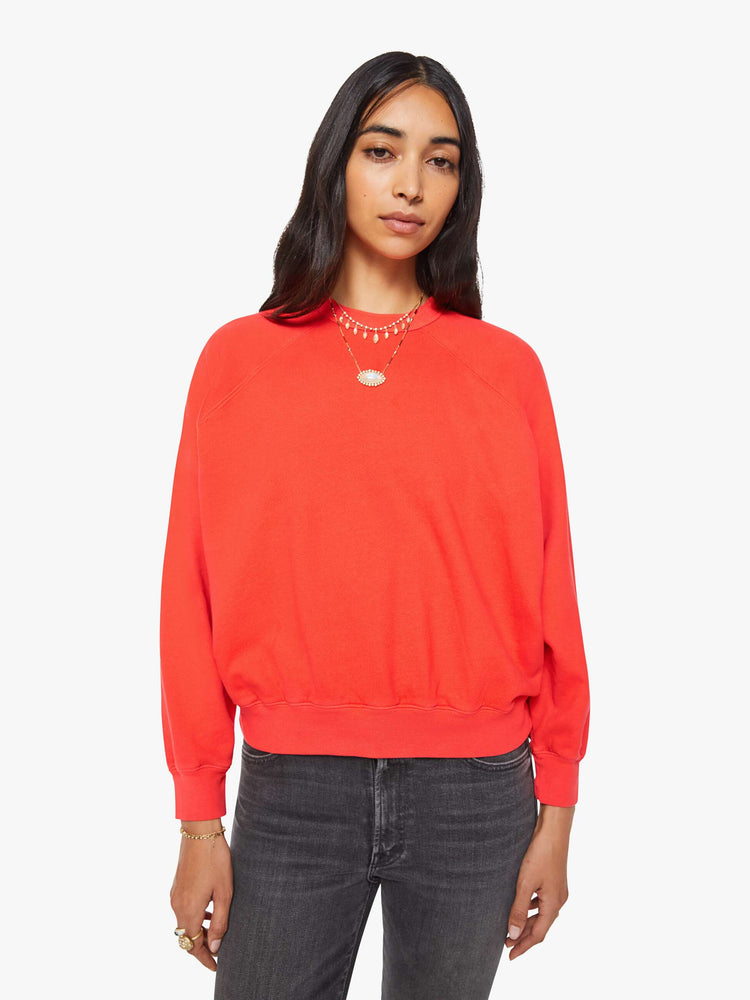 Front view of a woman in a bright orange  sweatshirt with a crewneck, ribbed hems and a slightly cropped fit. 