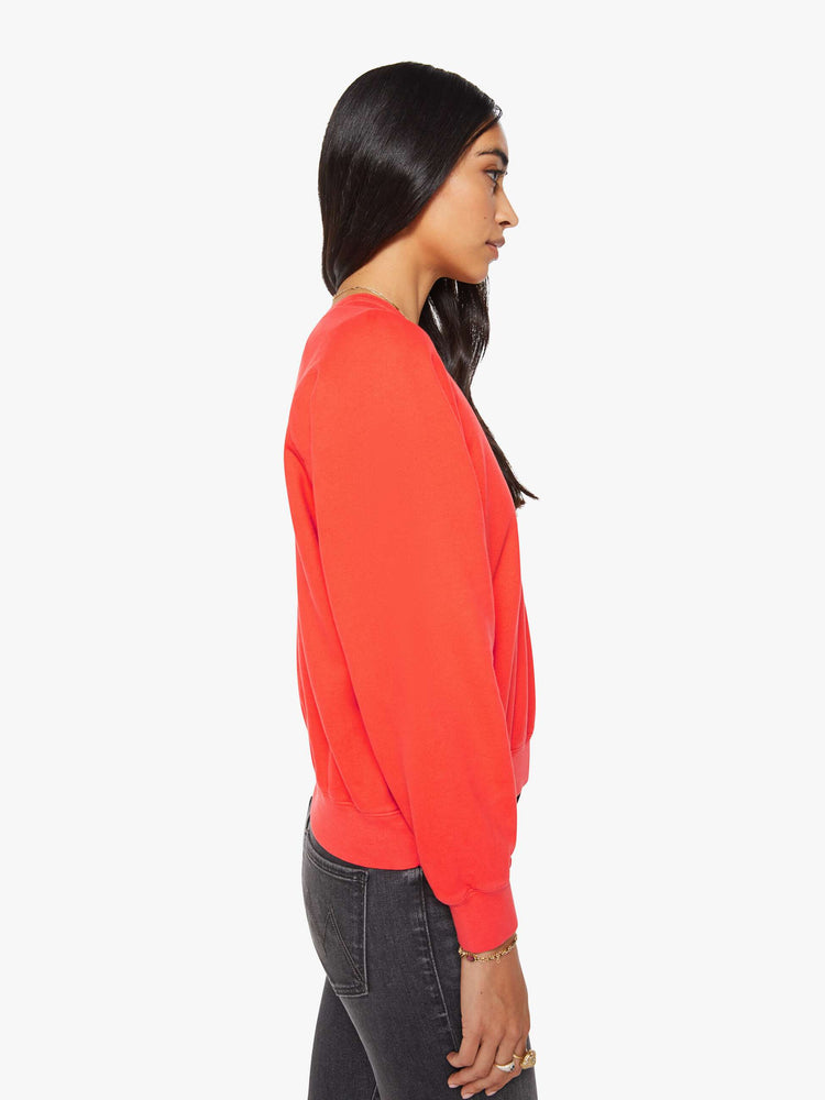 Side view of a woman in a bright orange  sweatshirt with a crewneck, ribbed hems and a slightly cropped fit. 