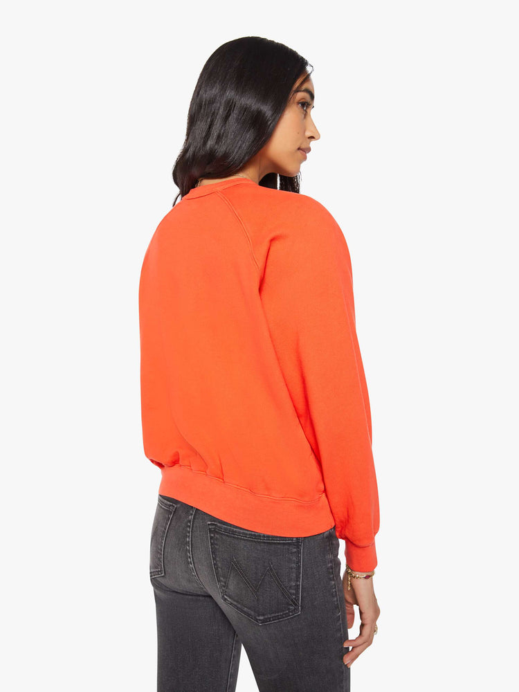 Back view of a woman in a bright orange  sweatshirt with a crewneck, ribbed hems and a slightly cropped fit. 