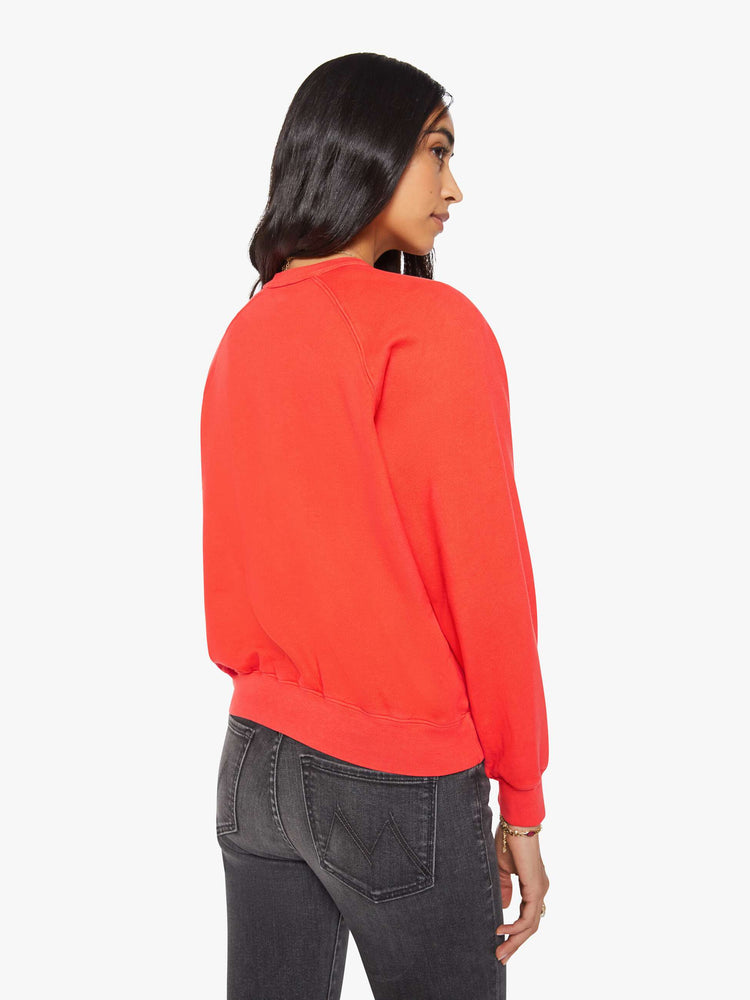 Back view of a woman in a bright orange  sweatshirt with a crewneck, ribbed hems and a slightly cropped fit. 