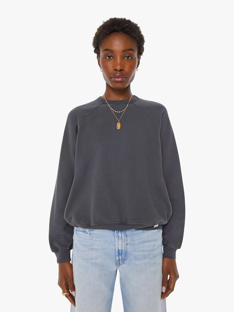 Front view of a woman in a faded black oversized raglan sweatshirt with a crewneck, ribbed hems and a slightly cropped fit.